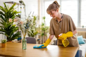 Young woman cleaning a modern living room with eco-friendly supplies, representing professional residential cleaning services by Natura Clean."